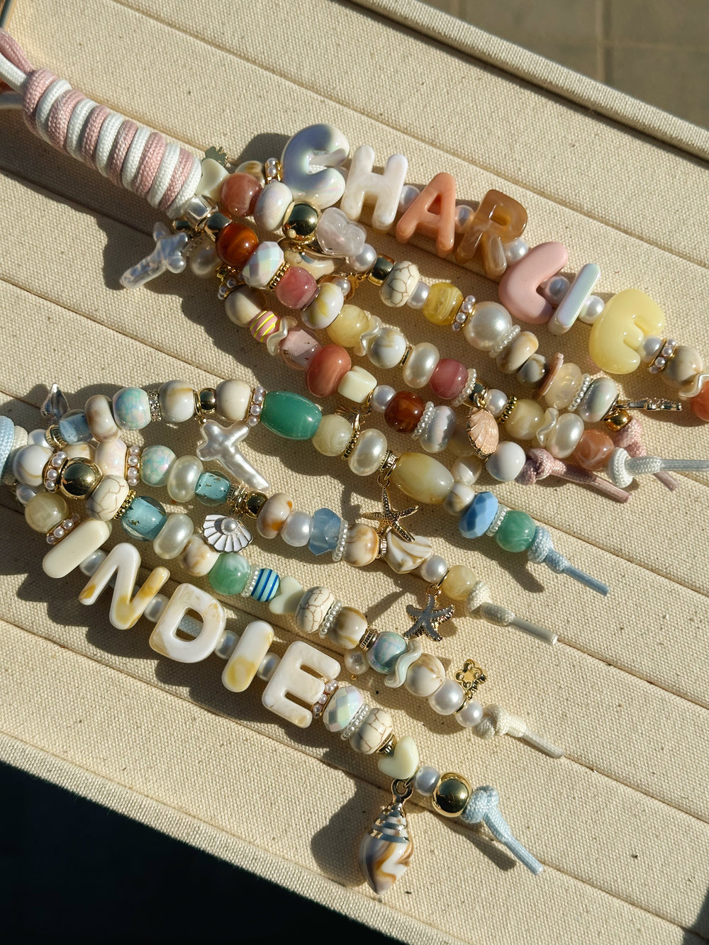 Two Lucky Loop charms spelling Charlie and Indie in cream, pearl and sea-glass beads