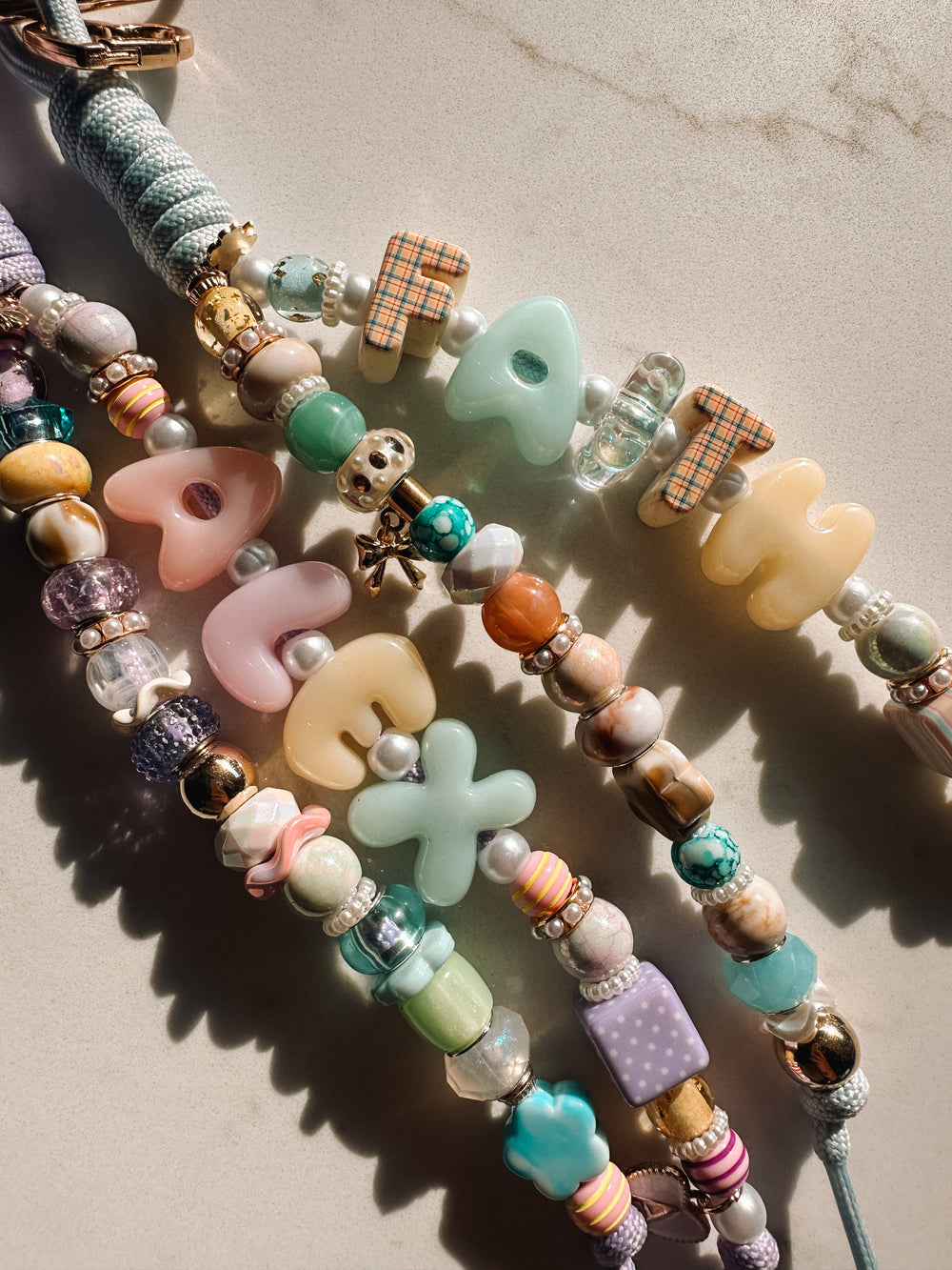 Pastel Lucky Loop charms spelling Faith and Grace in sunlight