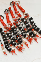 Red and black personalized bag charms clipped together, names spelled in black letter beads