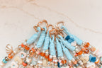 Close-up of rose gold heart clasps on a group of light blue beaded bag charms