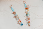 Two coastal blue Lucky Loop charms on marble, one spelling Liv and one spelling Sarah