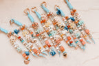 Coastal blue personalized bag charms arranged in a row on a marble surface