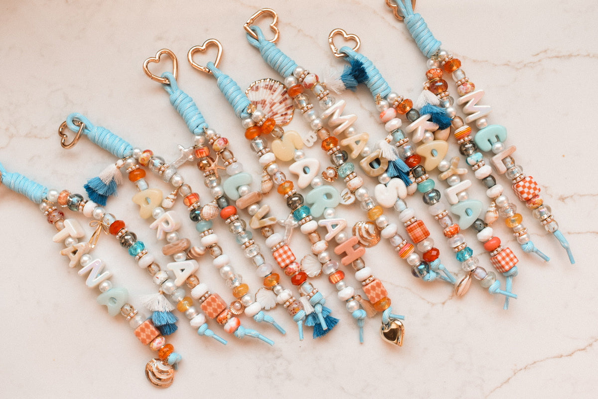 Coastal blue personalized bag charms arranged in a row on a marble surface