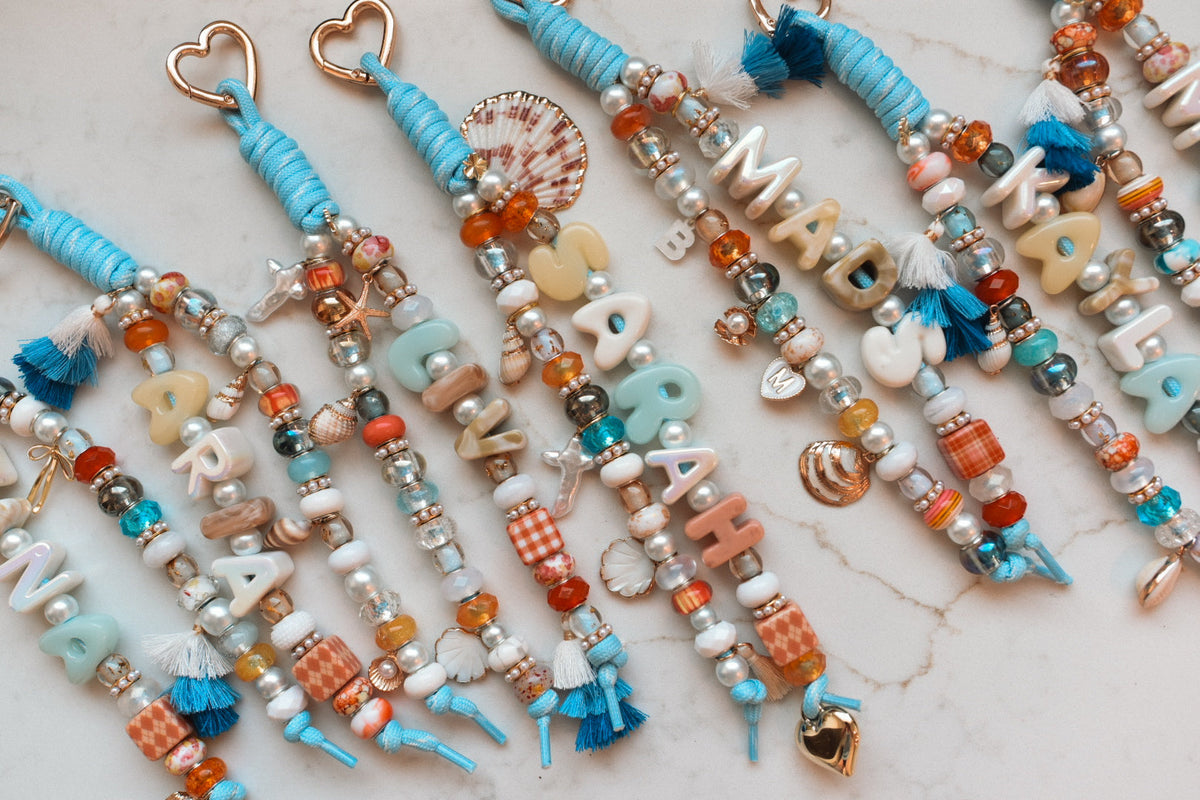 Close-up of coastal blue name charms showing the pearl, shell and tassel beadwork