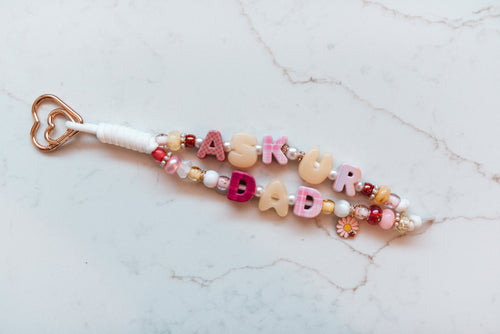 Ask Your Dad 2-strand loop in pink plaid and cream with ASK UR DAD letter beads, a pink daisy and ladybug charm and a rose gold heart clasp
