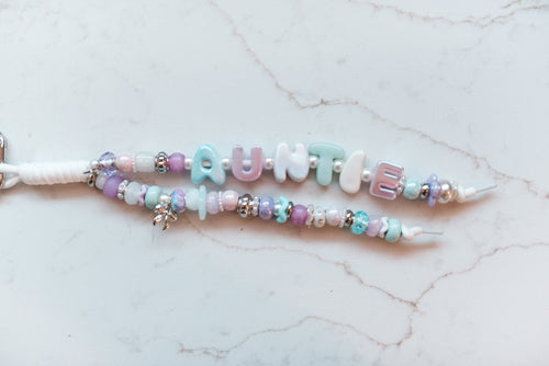 Auntie Pastel 2-strand loop in lavender, mint and aqua with AUNTIE bubble letters, silver accents and a silver bow charm on a white cord