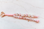 Pilates Princess loop close-up showing iridescent PILATES letters and a gold dumbbell charm
