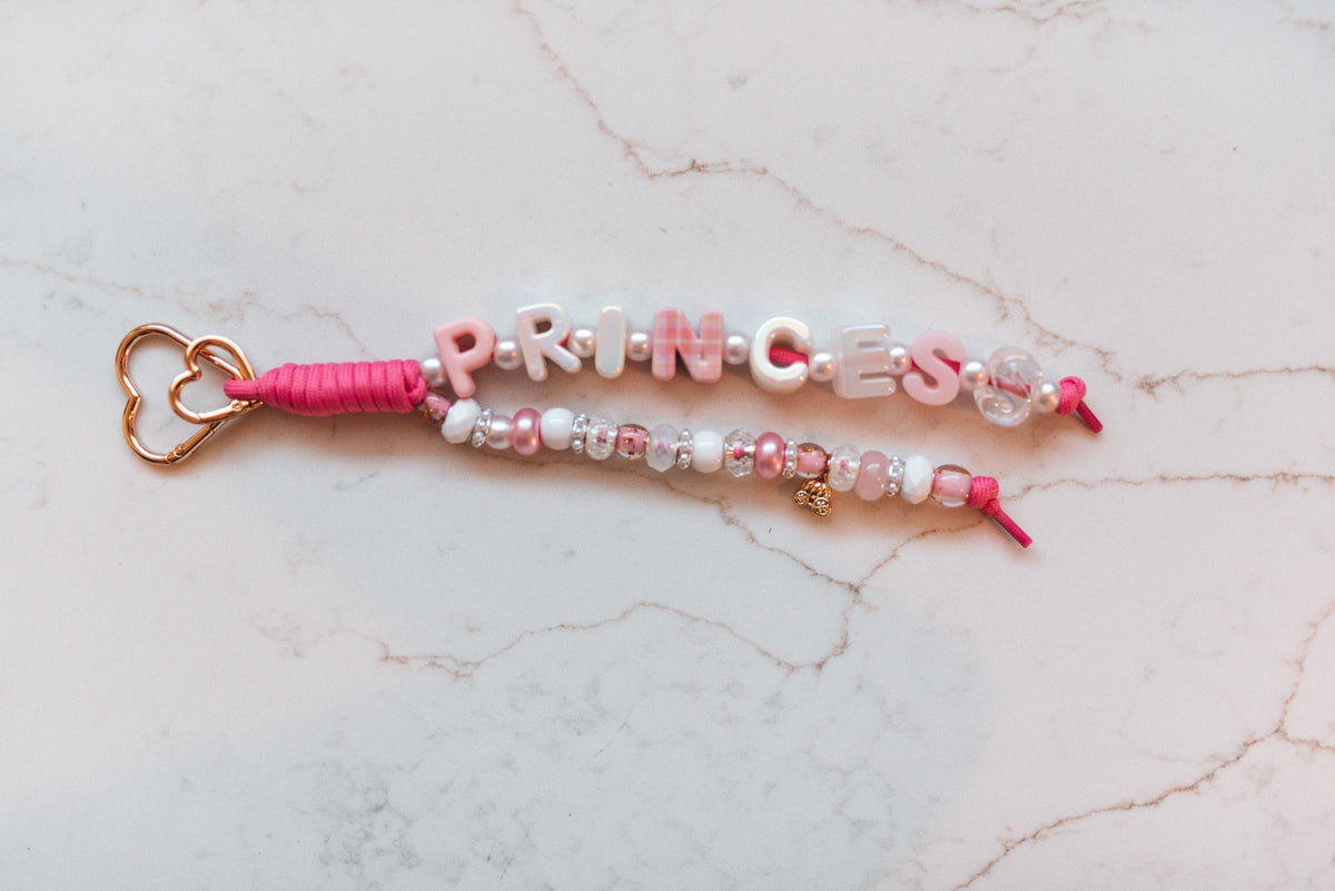 Princess 2-strand loop in pink and white with PRINCESS letter beads, sparkle beads, a gold carriage charm and a rose gold heart clasp