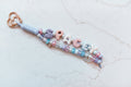 Spacey 2-strand loop in pastel lavender, pink and sky blue with SPACEY bubble letters, a planet charm, a cloud charm and a rose gold heart clasp