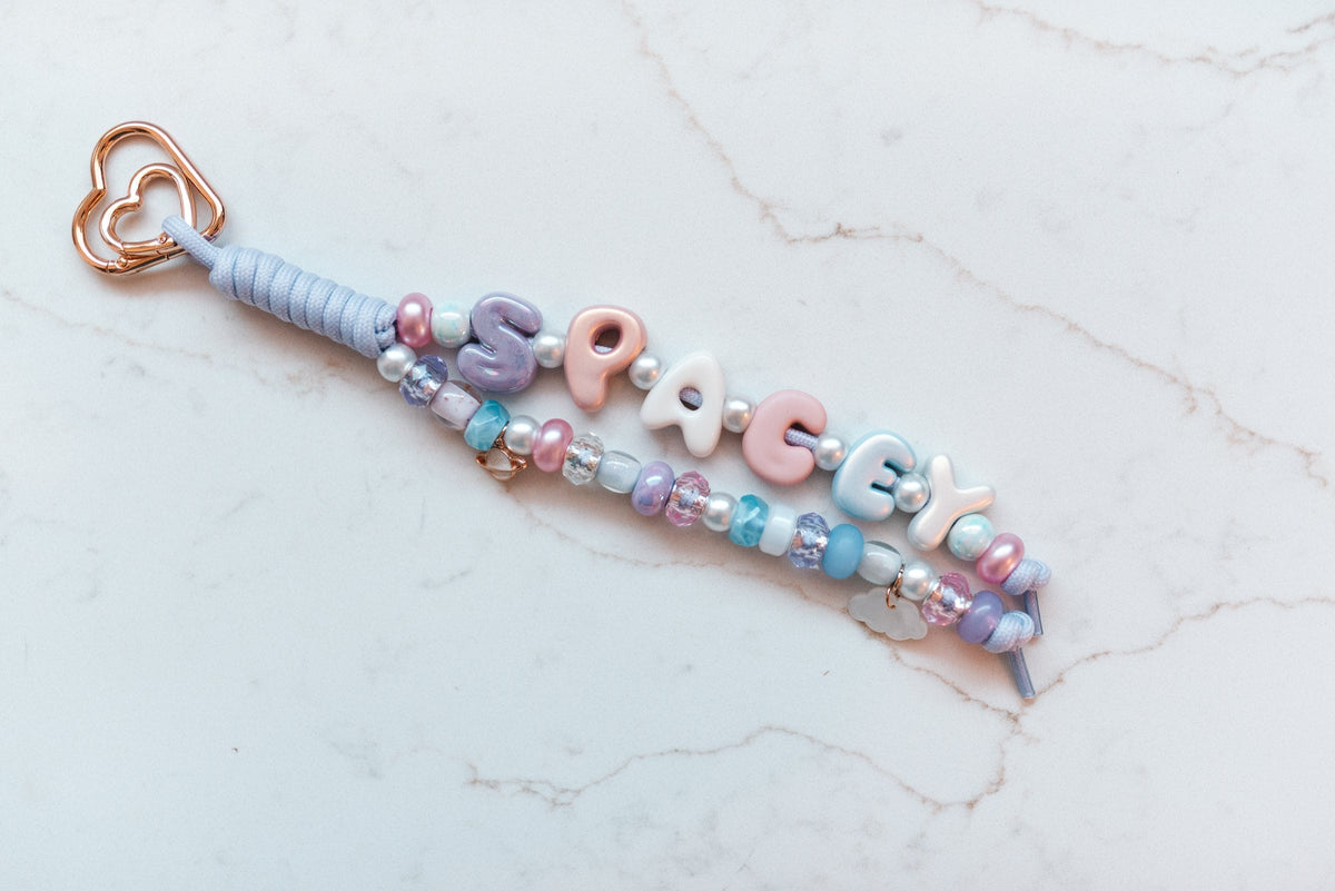 Spacey 2-strand loop in pastel lavender, pink and sky blue with SPACEY bubble letters, a planet charm, a cloud charm and a rose gold heart clasp